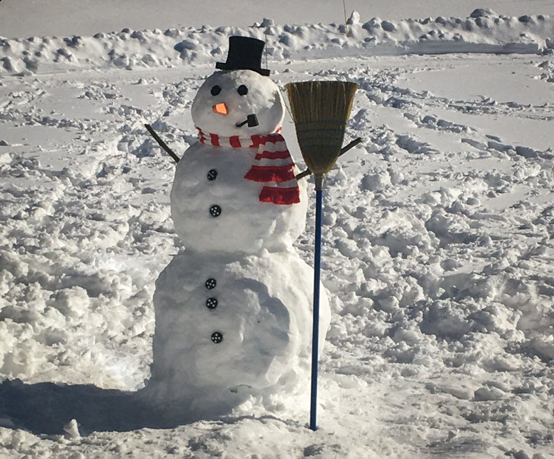 A snowman holding a broom.