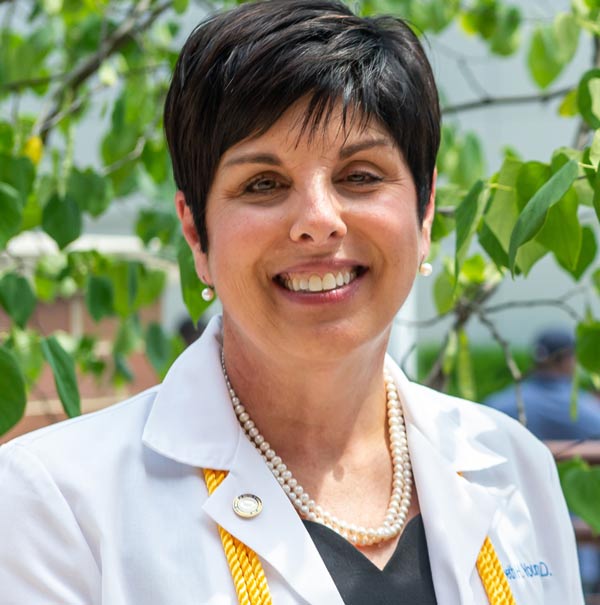 Dr. Lisa Young in a white coat, standing outdoors.