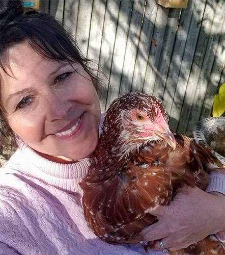 A woman holding a chicken.