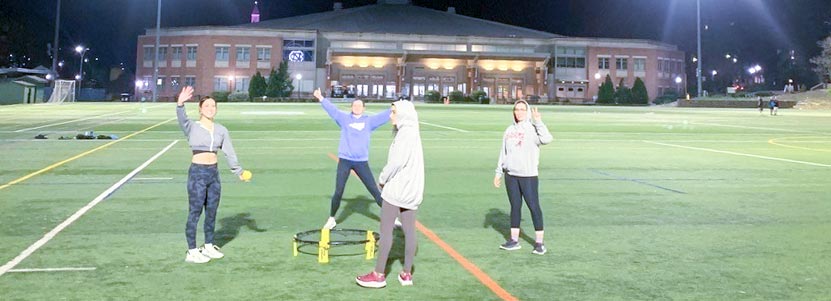 Students playing spikeball on a University field.