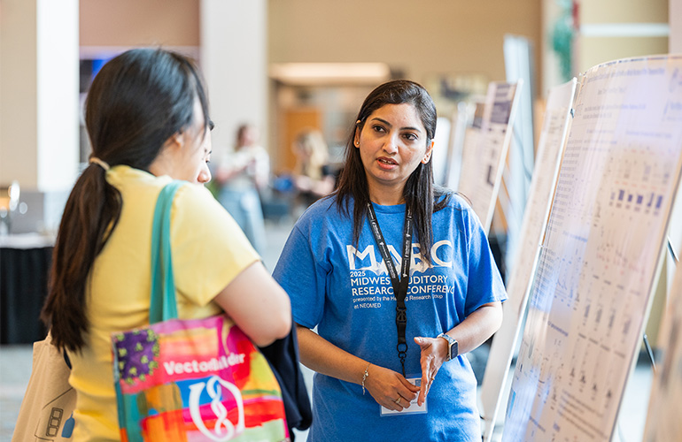 Young woman in blue MARC T-shirt explains something to a women in a  yellow T-shirt