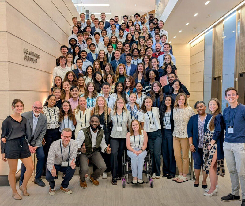 A large group of people smile while posing on stairs