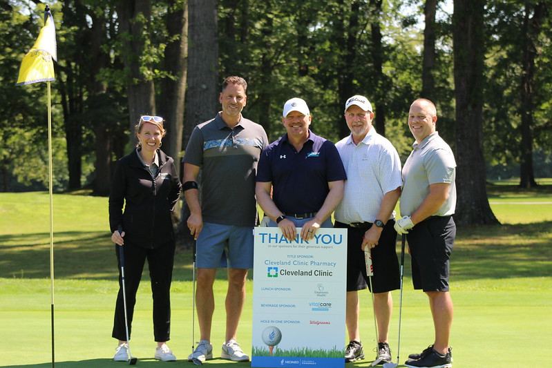 A group of five golfers holds a sign thanking sponsors for support.