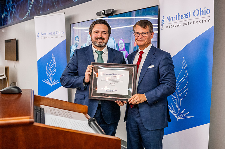 Dr. Thomas Mike accepts an award from Dr. John Langell