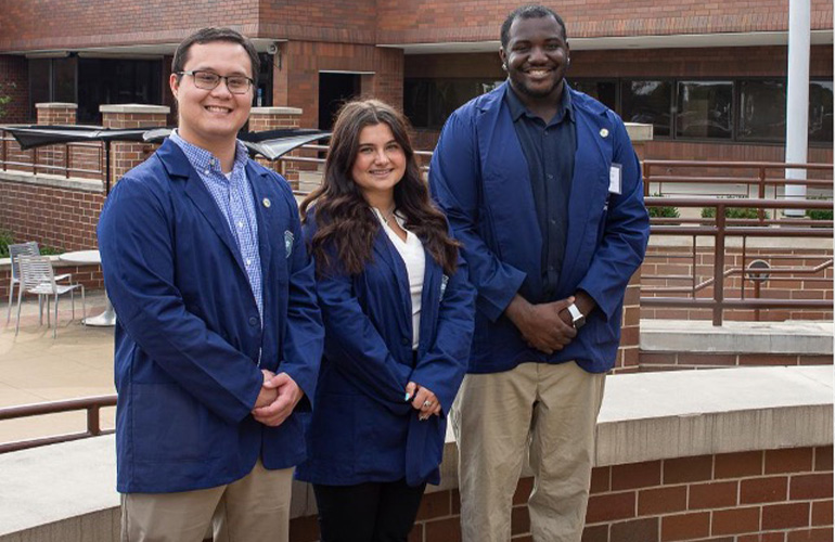 three AHEC scholars smile for the camera after receiving their Blue Coats