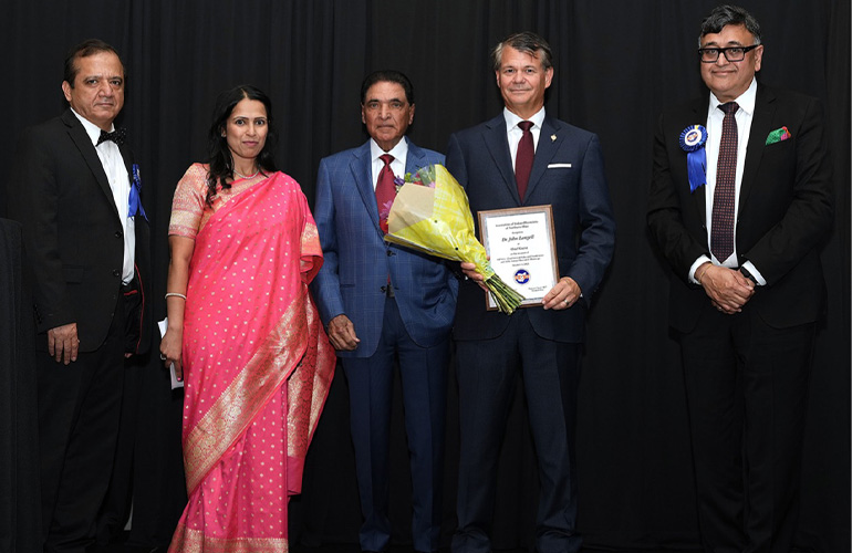 Four men in suits and a woman in pink traditional garb.