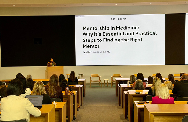 Conference hall with screen reading "Mentorship in Medicine: Why it's essential and practical steps to finding the right mentor"