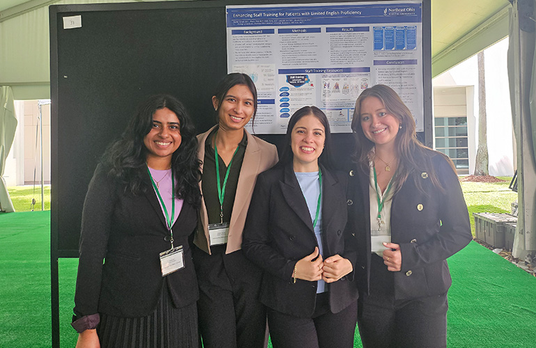 group of women stand in front of an academic poster
