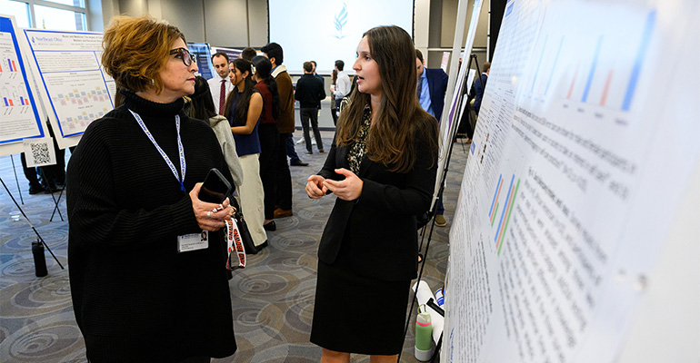 Young woman explains her scientific poster to a visitor