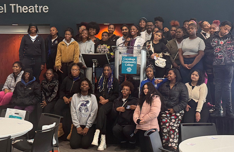 a large group of young people pose around a podium with the Tri-C logo on it