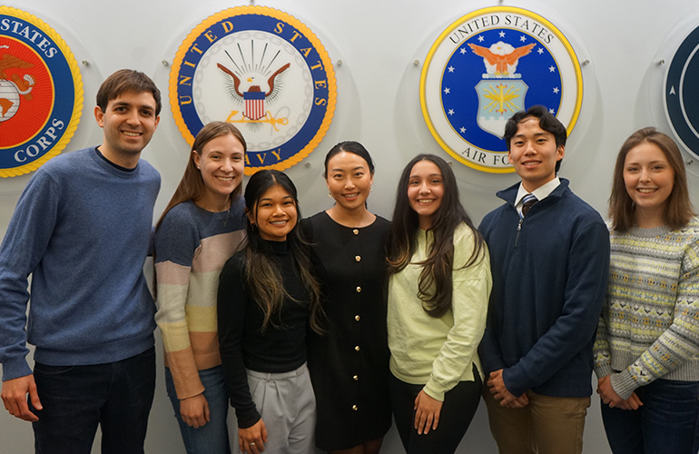 Group of young people pose in front of military seals