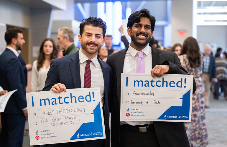 Two young men hold signs saying "I matched"