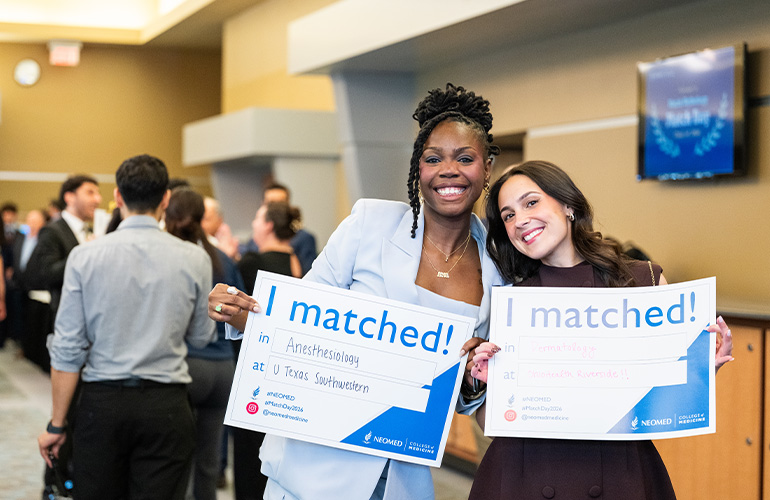 Two young women hold signs saying "I matched"