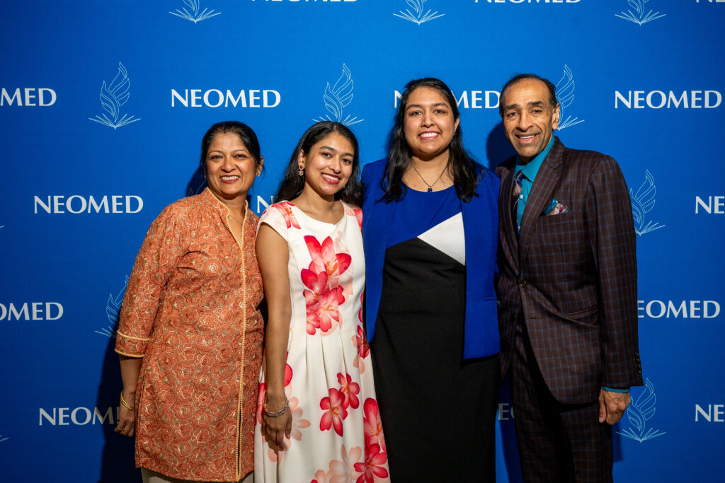 Members of the Agarwal family pose in front of a NEOMED backdrop