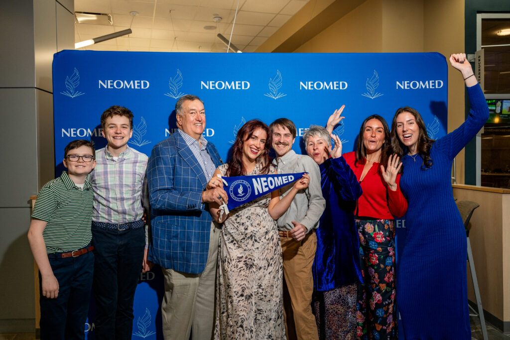 Members of the Cmolik family pose in front of a NEOMED backdrop