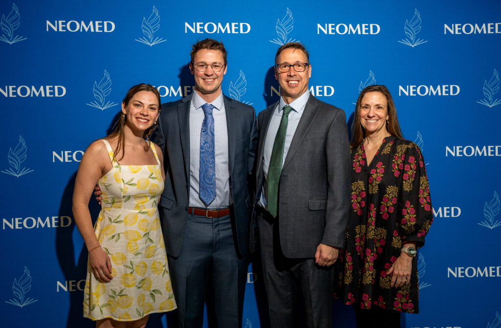 Members of the Hergenrother family pose in front of a NEOMED backdrop