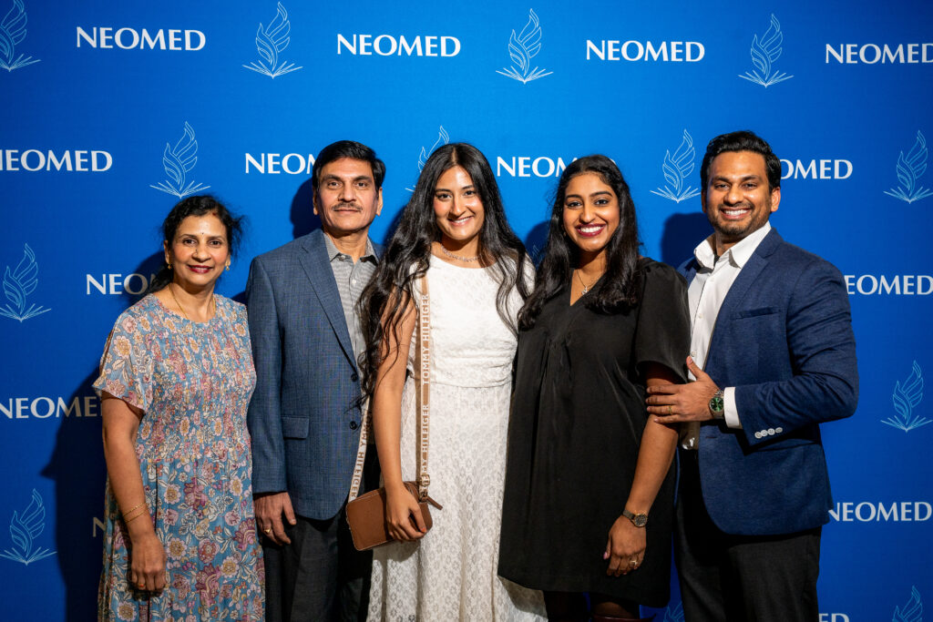 Members of the Korada family pose in front of a NEOMED backdrop