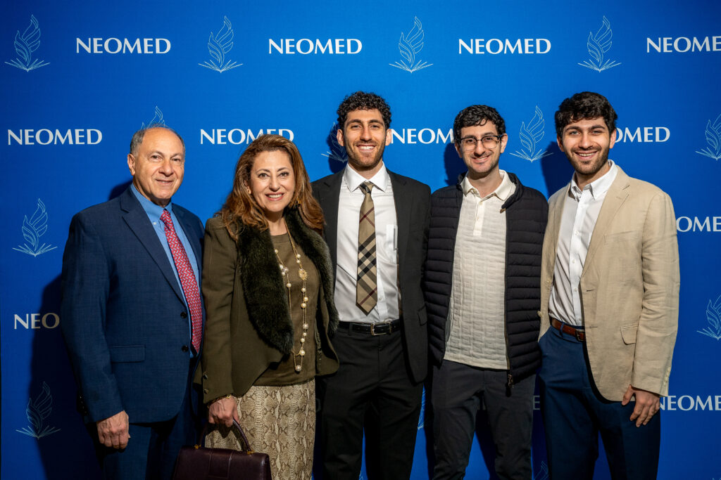 Members of the Muakkassa family pose in front of a NEOMED backdrop