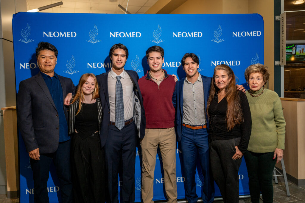 Members of the Wu family pose in front of a NEOMED backdrop