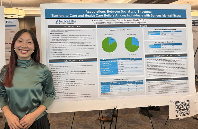 Young woman in green shirt poses with an academic poster