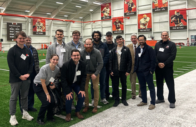 a group people in street wear pose on an indoor training field for football 