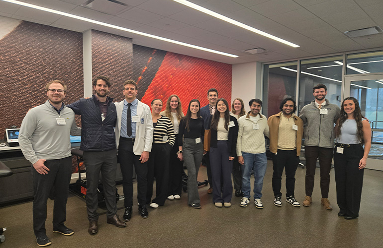 A group of people in casual clothing pose in an athletic training facility