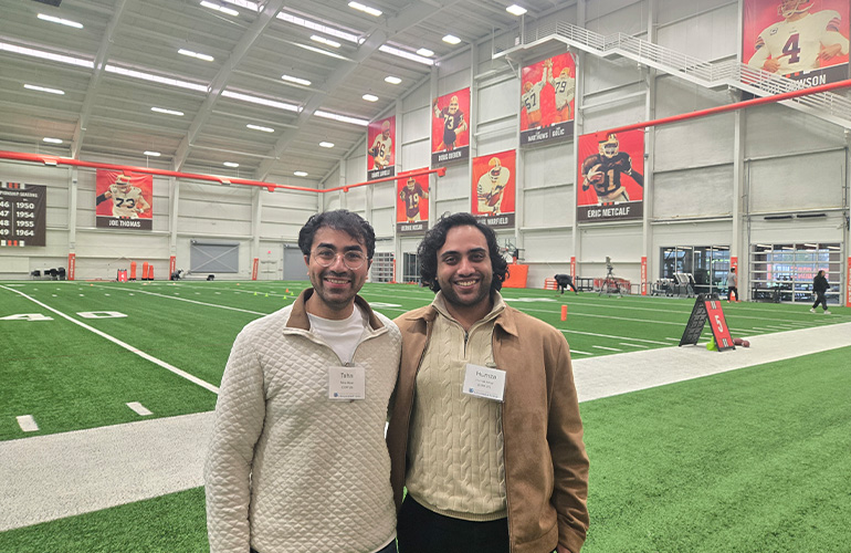 The Akbar brothers pose on an athletic training field