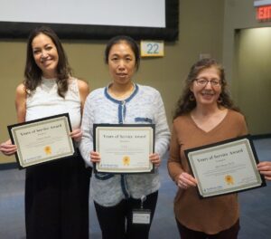 Three women pose with certificates of award