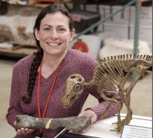 Portrait of Holly Ballard with a small model of a dinosaur skeleton