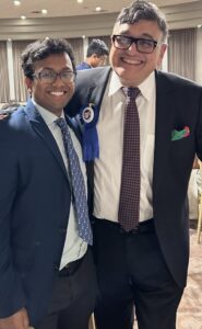 Two men in suits smile at the camera