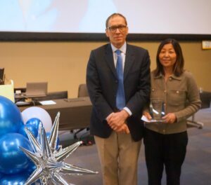 A man and woman in suits pose in a large conference hall