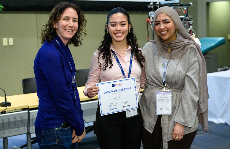 Three women in business attire pose with an oversized check