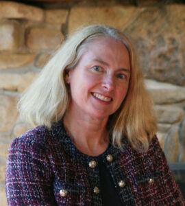 Portrait of Dr. Sara Whittingham seated in from of a stone wall