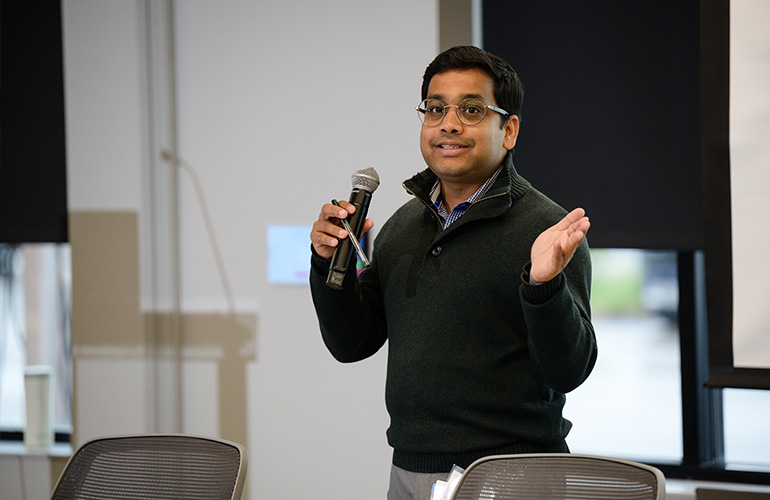 Dr. Samudragupta Bora speaks into a microphone while gesturing toward the audience