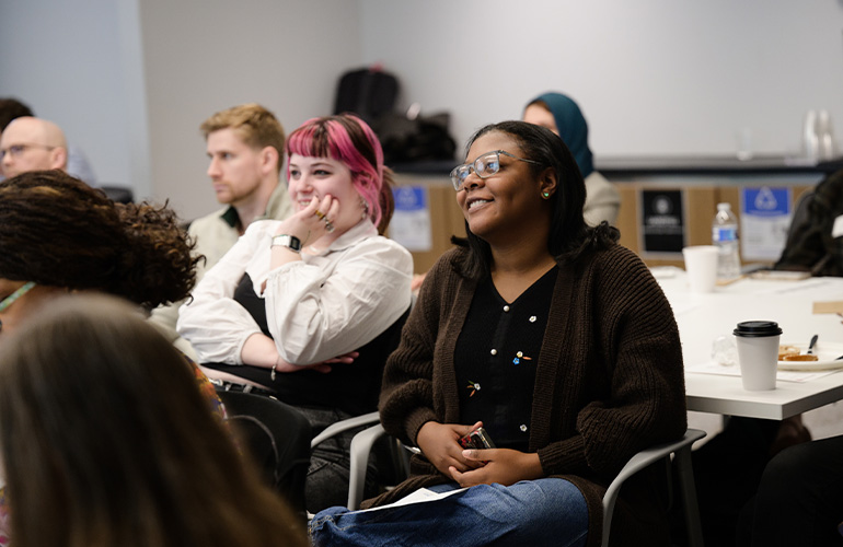 Two young women listen intently to a presentation while seated in a meeting room