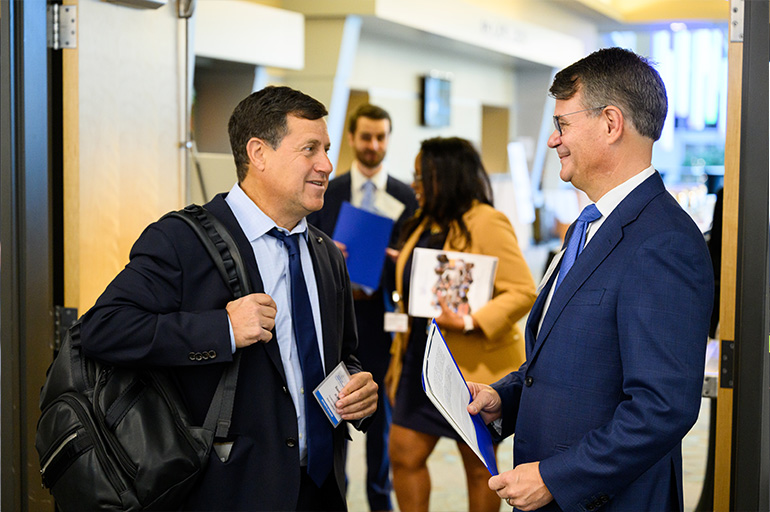 two men in suits and ties chat in a doorway