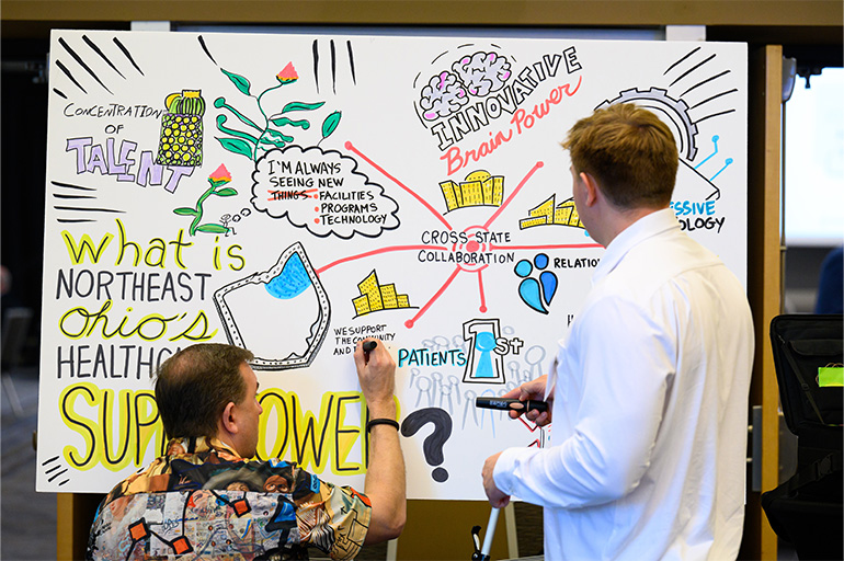 two men with their backs to the camera work on a colorful poster