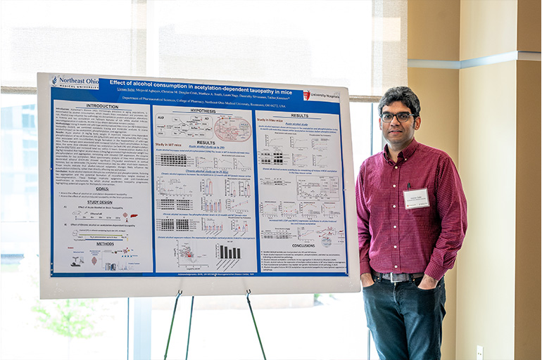 a man in a red shirt stands next to an academic poster