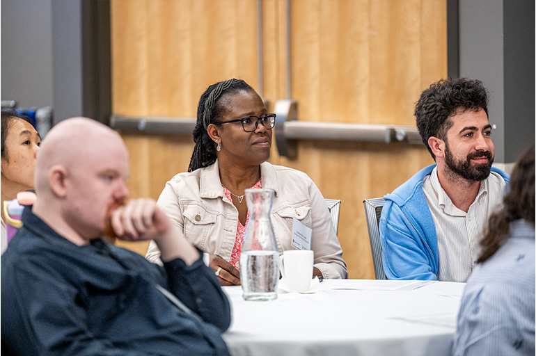 a group of people sit at a table listening intently to an unseen speaker