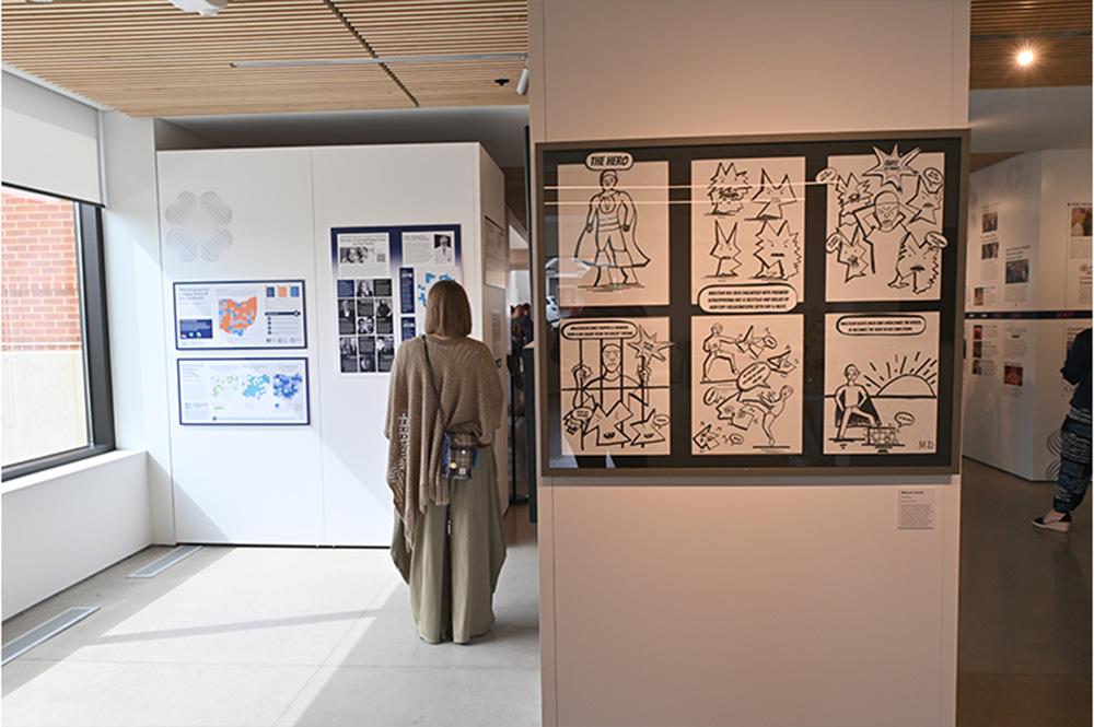 a woman with her back to the camera explores the exhibit in Peg's Gallery