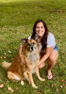 a woman in casual summer attire plays poses with a fluffy dog