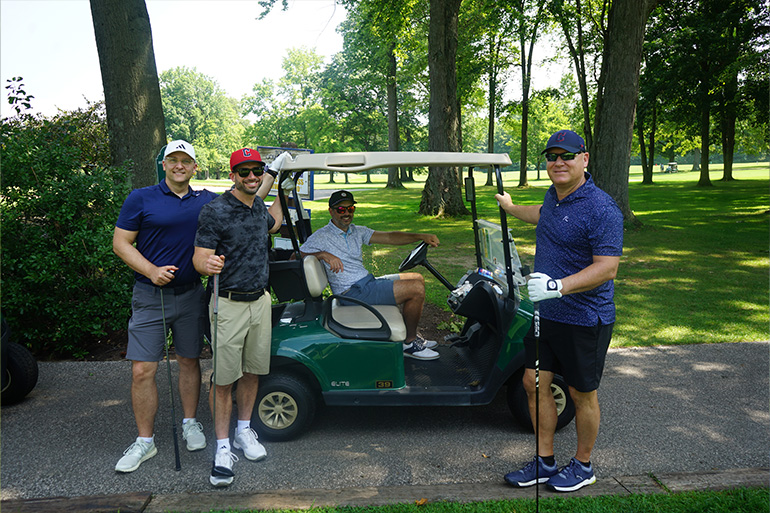 a man is seated in a golf cart surrounded by three other golfers