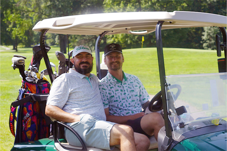 two men ride in a golf cart