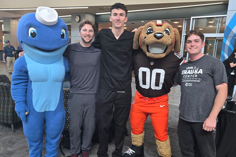 three young men pose with Nate the Walking Whale and Chomps the dawg