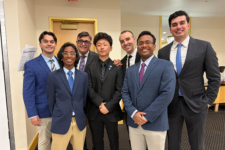 A group of men in suits pose in a line and smile at the camera