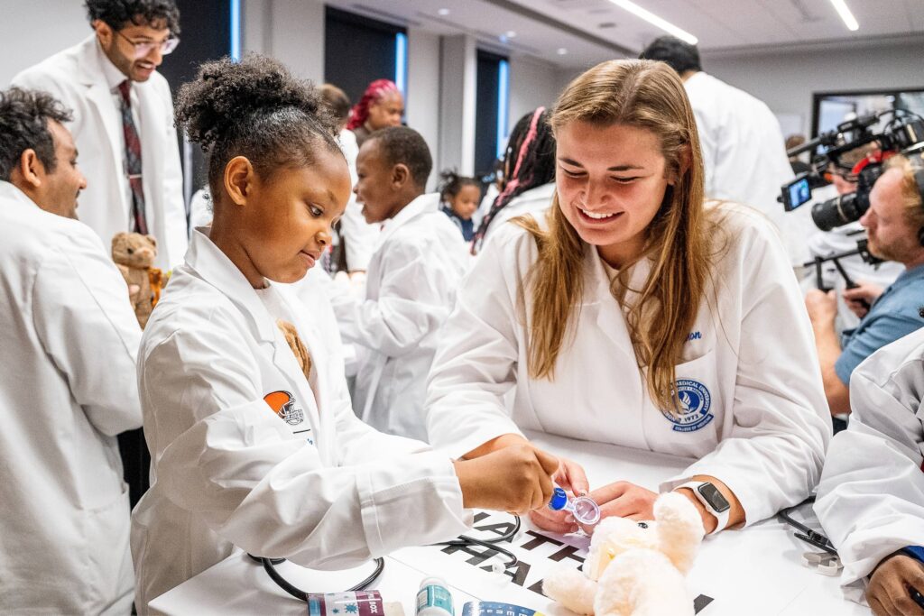 A woman and child, both wearing white coats, work on a coloring project together