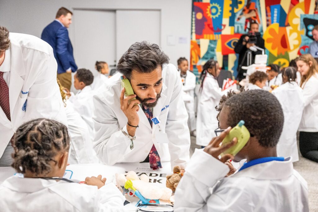 a man in white coat has a serious conversation on a plastic walkie talkie with a child in a white coat